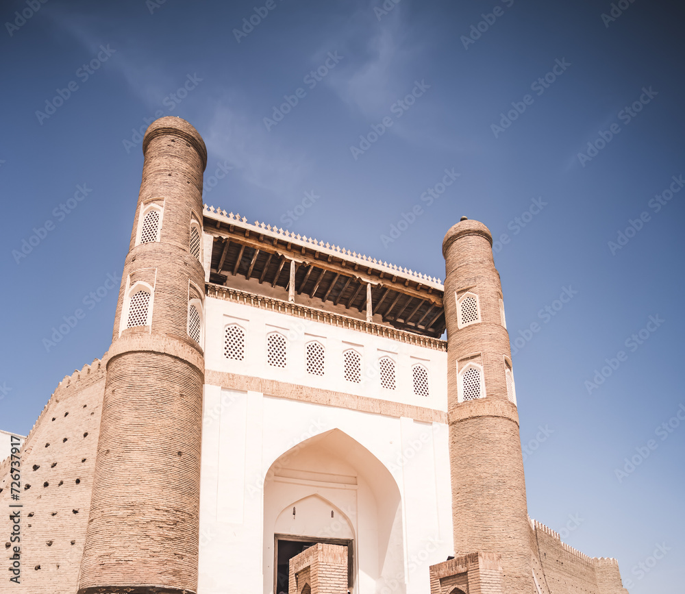 Entrance gate to the Ark Citadel with fortress walls made of bricks in the ancient city of Bukhara in Uzbekistan on a warm summer sunny day, fort made of stone