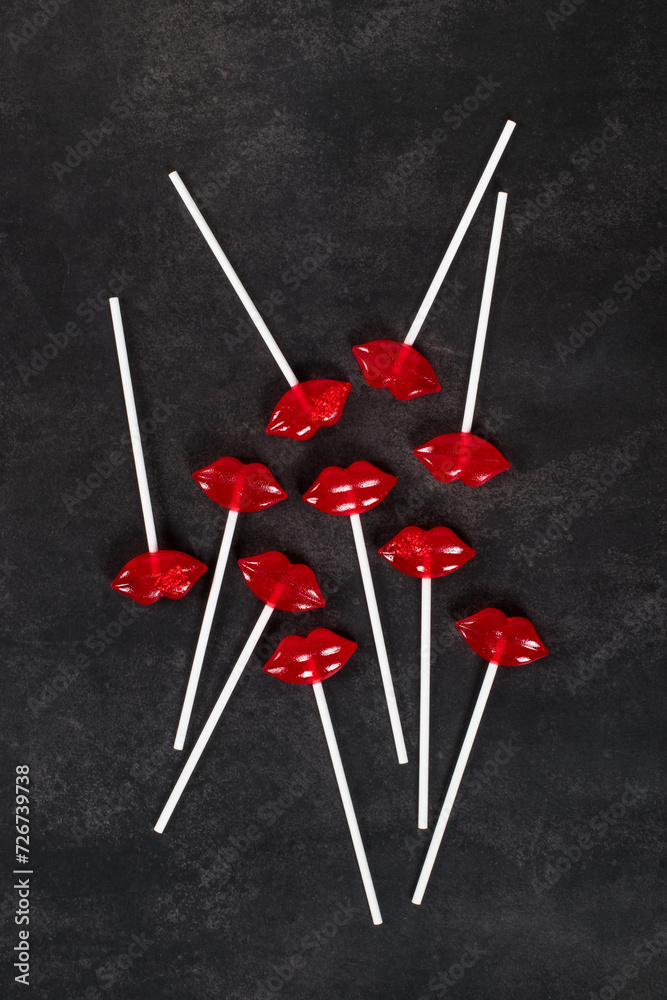 Holiday Red lips lollipops on a paper stick. Dark background. Top view. Valentine's day Holiday Red lips lollipops on a paper stick. Dark background. Top view. Valentine's day