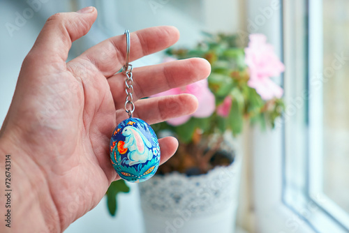 Keychains in the form of Ukrainian Easter egg with Petrykivka painting in the palm. Hand-painted wooden decor.