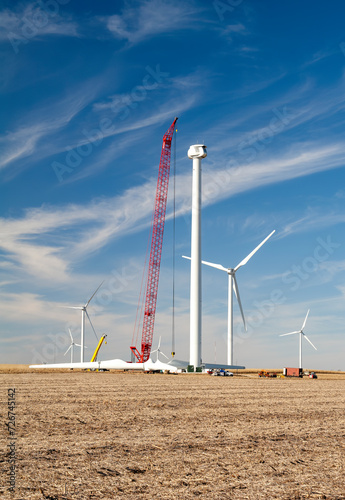Clean energy producing wind turbine under construction  while surrounded by crops