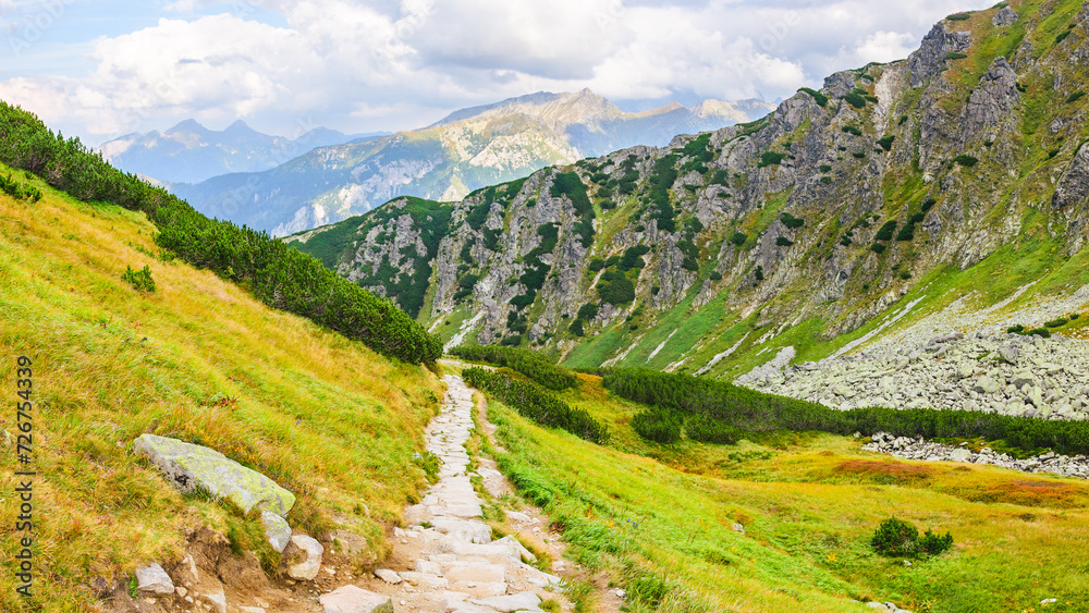 Naklejka premium Polish Tatra Mountains, high mountain hiking trail leading to mountain peaks, mountain landscape with valleys and slopes, view on a sunny summer day.