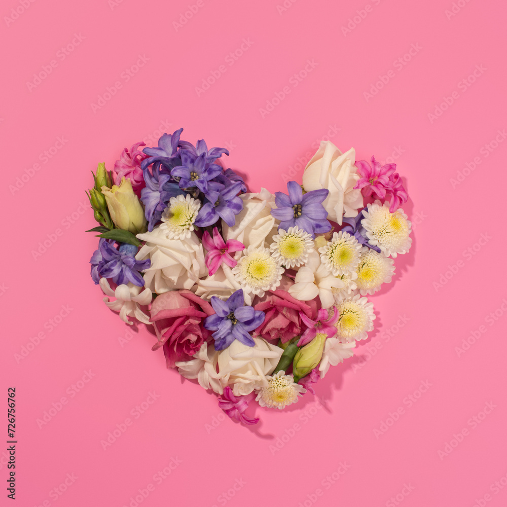 heart made of different flowers on a pink background