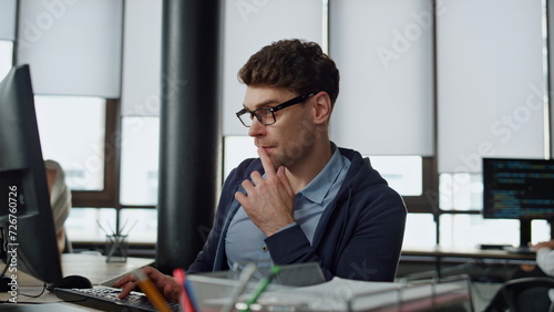 Computer guy looking screen on office. Thoughtful engineer checking code problem