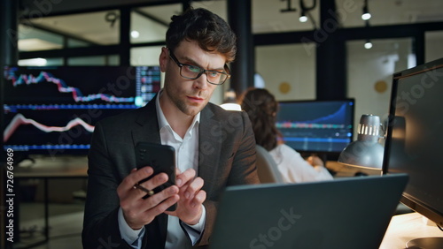 Stock trader holding smartphone work in office. Focused man professional check photo
