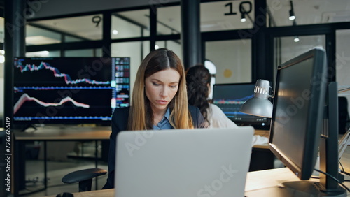 Finance broker working computer at investment graph. Focused woman analyze stock