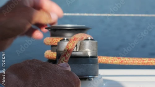 Skillful sailor fixes sails by wrapping rope around halyard. Captain of sailboat exactly knows how to guide vessel in right place