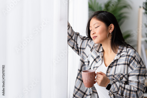 Chinese happy woman in a daydreaming at home enjoying coffee in the morning Free Download Chinese happy woman in a daydreaming at home enjoying coffee in the morning - GFXLoad