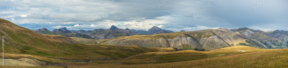 Mountain tundra meadow after storm with dramatic lighting and distant peaks