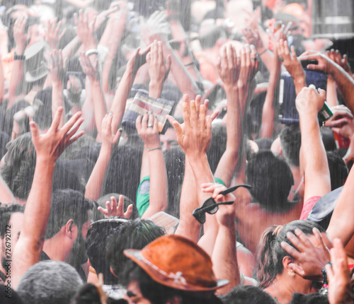 People with arms raised receiving rain from a hose at the carnival party with revelers in this folkloric and popular festival