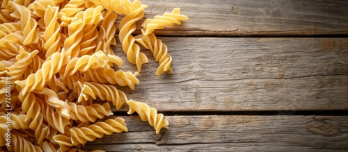 Wooden background with dried fusilli pasta in corkscrew shape.
