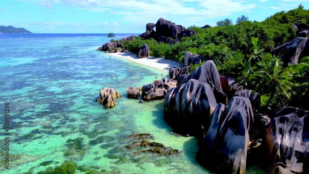 Anse Source d'Argent beach, La Digue Island, Seychelles, Drone aerial view of La Digue Seychelles bird eye view. of tropical Island, couple men and woman walking at the beach at a luxury vacation