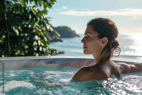 girl relaxing in a hot tub  with a view of the ocean in the background