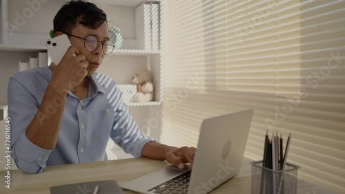 Man Multitasking, Typing on Laptop and Talking on Phone at Home Office , Home Workspace, Very busy with work.