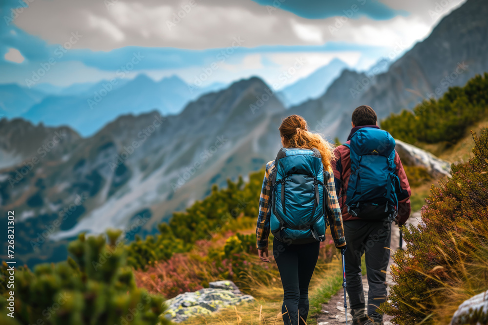 man and a woman hiking up a mountain trail, with backpacks on their shoulders