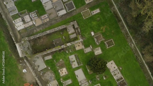 Drone zenithal top down view rotates above cemetery plots and old church walls photo