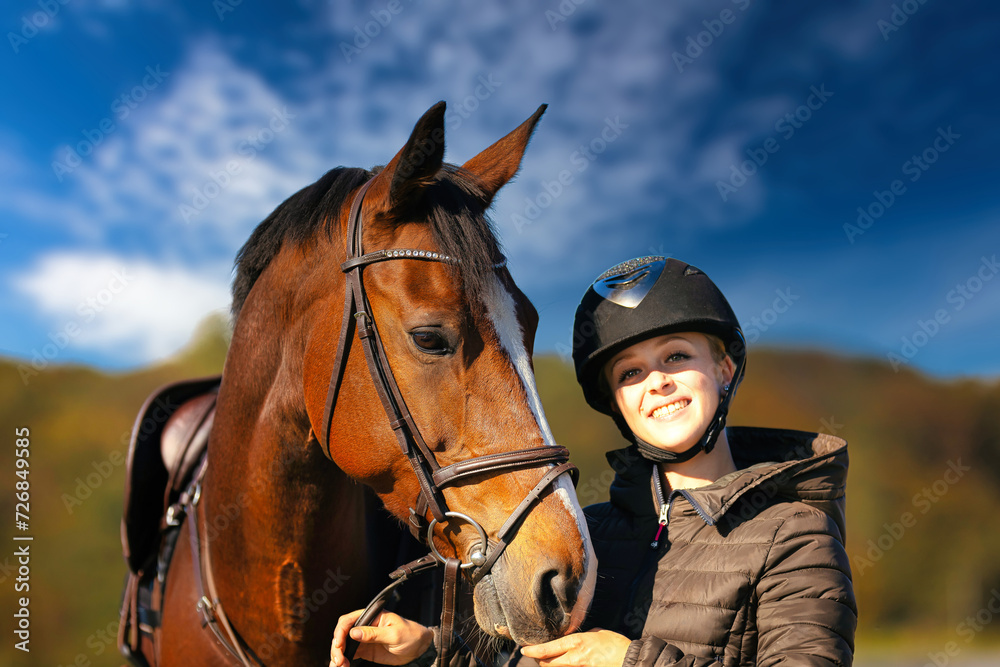 Obraz premium Horse head portraits in front of a blue sky and a rider standing next to it..