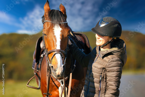 Horse head portraits in front of a blue sky and a rider standing next to it..
