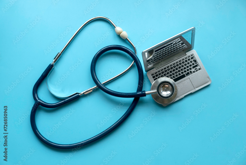 Stethoscope over a laptop over a blue background. Stethoscope over a laptop over a blue background.