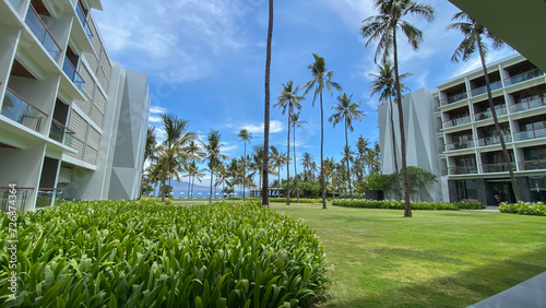 Banyuwangi, East JavaIndonesia-Des, 6th 2023: Tropical resort and hotel with green view of coconut trees and the grass. Isolated blue sky in Bali strait. photo