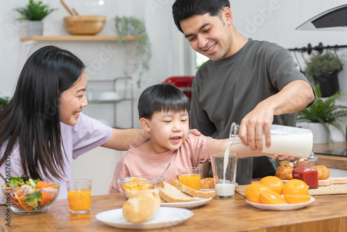 happy family together. Asian parent eating breakfast with little son in the kitchen.