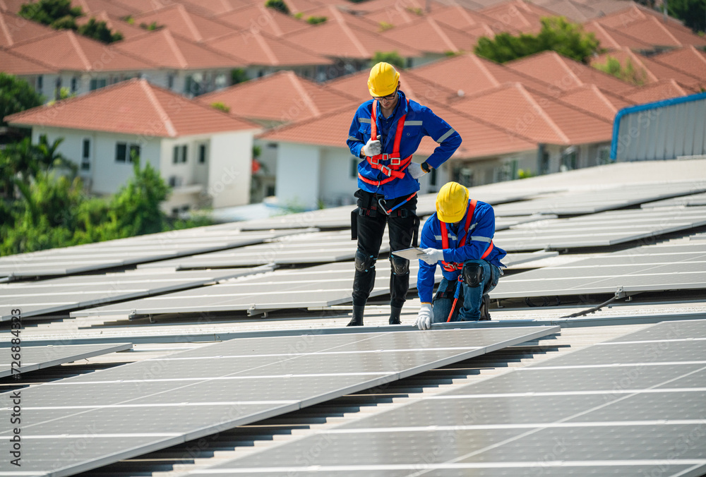 Men technicians carrying photovoltaic solar modules on the factory roof. Engineers in helmets installing solar panel systems outdoors. Concept of alternative and renewable energy solar cell. Men technicians carrying photovoltaic solar modules on the factory roof. Engineers in helmets installing solar panel systems outdoors. Concept of alternative and renewable energy solar cell.