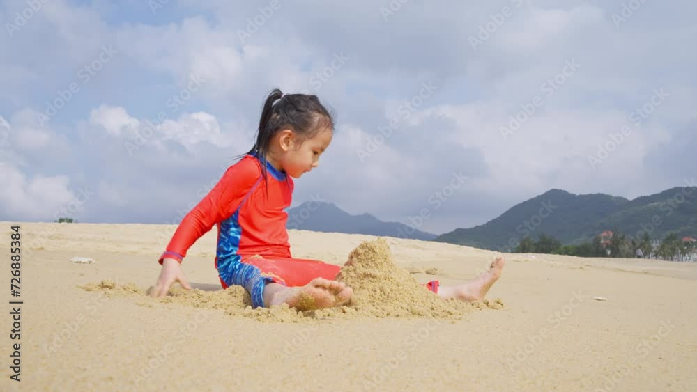 little asian girl building sand castle playing on the beach at Hainan China little asian girl building sand castle playing on the beach at Hainan China