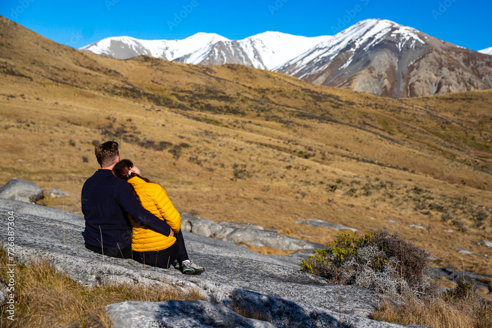 a couple of tourists enjoying the view of unique rock formations at castle hill conservation area near arthur's pass in new zealand alps; unique scenery in catnerbury mountains a couple of tourists enjoying the view of unique rock formations at castle hill conservation area near arthur's pass in new zealand alps; unique scenery in catnerbury mountains