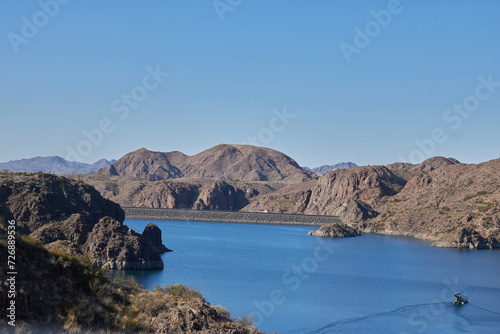 view of a raft sailing over the los reyunos reservoir and surrounded by mountains on a sunny day