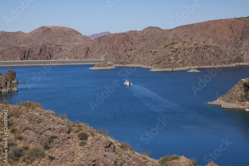 view of a raft sailing over the los reyunos reservoir and surrounded by mountains on a sunny day