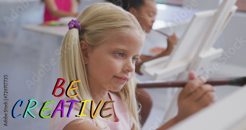 Image of be creative text in multi colours over happy caucasian schoolgirl painting in art class
