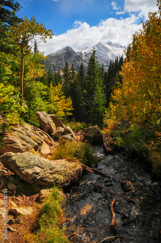 A creek on a forested valley surrounded by early fall foliage and snow-dusted peaks on the hike to Dream Lake, Rocky Mountain National Park, Estes Park, Colorado, USA. photo