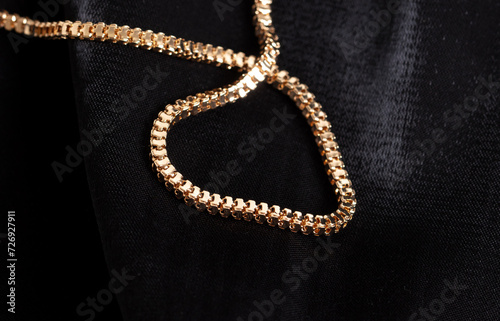 Gold chain on black silk fabric. Close-up