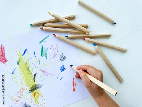 Wallpaper Mural small child draws with colored pencils on paper on white table. Torontodigital.ca