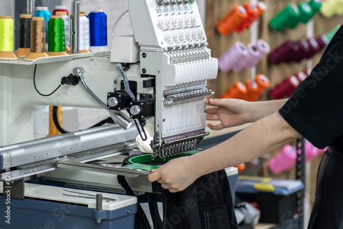 a female worker using and  preparing automatic tailoring machine for work  on clothing manufature factory photo