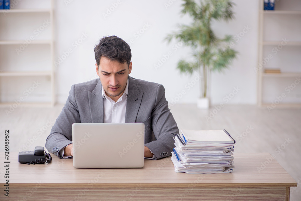 Young male employee and too much work in the office Young male employee and too much work in the office