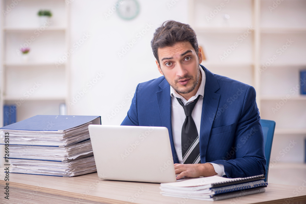 Young male employee and too much work in the office Young male employee and too much work in the office