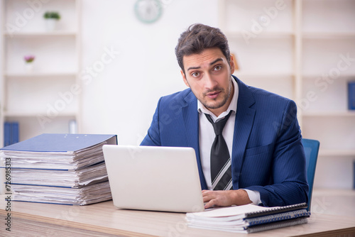 Young male employee and too much work in the office