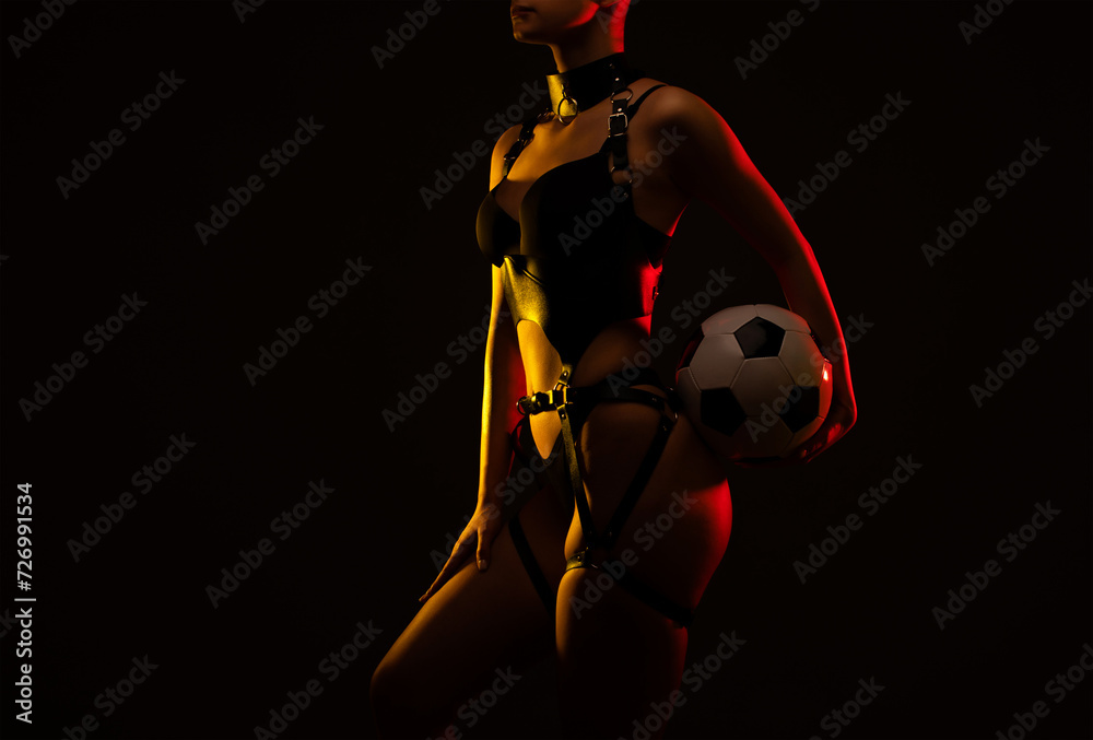 Beautiful girl body with black sexy underwear on a black background. She is holding a soccer ball in her hands. Sexy body, close up nudity. Beautiful girl body with black sexy underwear on a black background. She is holding a soccer ball in her hands. Sexy body, close up nudity.