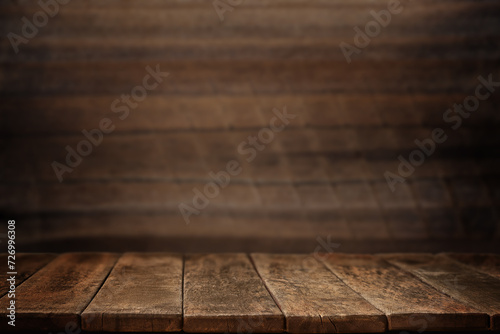 Empty wooden table against a dark wooden wall. Old planks wall and table with light empty space. Vintage wooden background