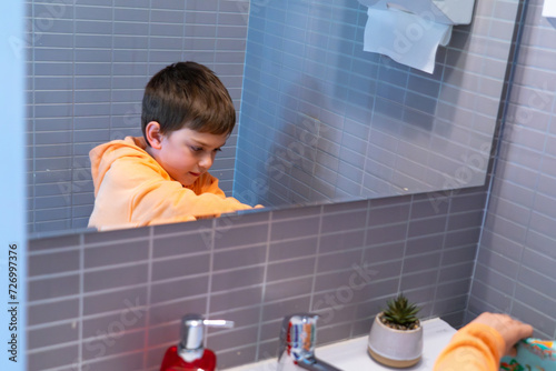 Boy at bathroom sink reflected in mirror