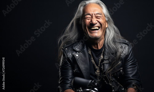 Joyful elderly Native American man with long silver hair laughing heartily, exuding a carefree spirit and timeless style in a classic black leather jacket