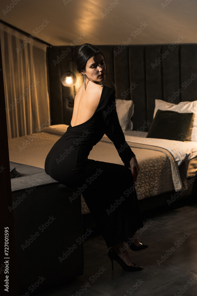 Elegant woman in a black dress posing in an apartment. Fashion shooting concept Elegant woman in a black dress posing in an apartment. Fashion shooting concept