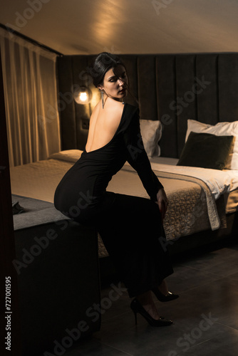 Elegant woman in a black dress posing in an apartment. Fashion shooting concept