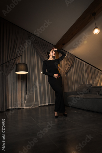 Elegant woman in a black dress posing in an apartment. Fashion shooting concept