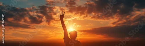 silhouette of a man holding up a peace sign at the sunset