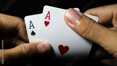 Closeup of a person hand holding a pair of aces against a dark background. Ideal for poker, blackjack, gambling, and casino concepts. photo