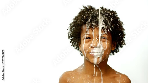 Milk is pouring on a dark-skinned boy. Acting skill of a little boy. photo