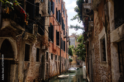 A narrow canal in Venice, Italy, with buildings on both sides and a boat floating in the water.