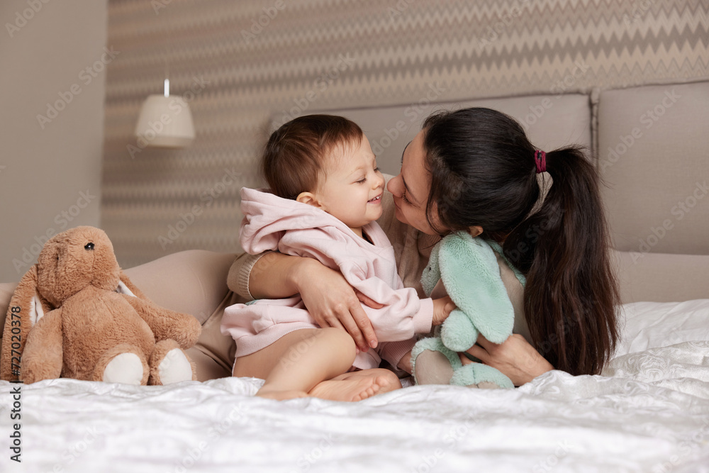 happy mother and her little child daughter playing with bunny toys in bedroom, family having fun happy mother and her little child daughter playing with bunny toys in bedroom, family having fun