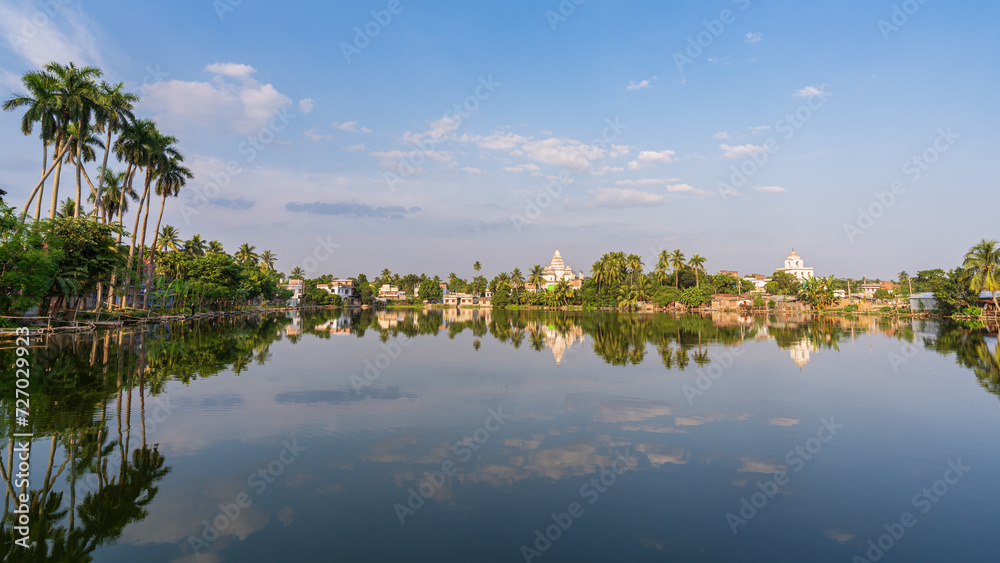 Scenic landscape panorama with Bhubaneshwar Shiva temple and houses reflection in lake, Puthia, Rajshahi, Bangladesh